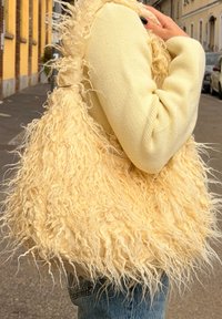 Borsa a tracolla gialla soffice con materiale testurizzato e peloso. Corpo ampio e morbido con un'ampia apertura, portata sotto il braccio. Design casual e oversize.