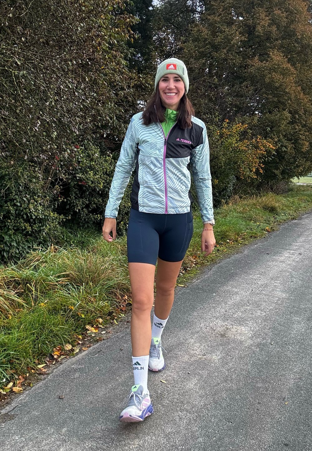 Ελαφρύ, μοτίβο σακάκι σε πράσινους και μαύρους τόνους, συνδυασμένο με σκούρες κοντές παντελόνες. Αθλητικά παπούτσια με παστέλ λεπτομέρειες, λευκές κάλτσες και σκουφάκι.