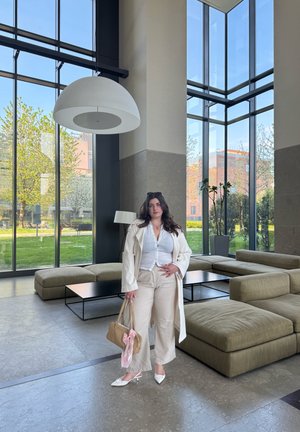 Sofá de tela beige con grandes cojines, mesa de café negra y ventanales de suelo a techo. Una lámpara colgante en forma de cúpula blanca cuelga por encima.