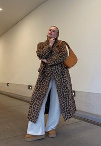 Καμπαρτίνα λεοπάρ, γκρίζες παντελόνες φαρδιές, καφέ πλατφόρμες μπότες και καφέ τσάντα ώμου. Λείες υφές, αντιθετικά σχέδια και χρώματα.