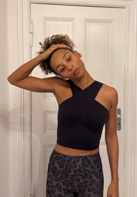 Czarny krótki top o asymetrycznym kroju, wykonany z elastycznego materiału. Połączony z szarymi legginsami w panterkę, wyposażonymi w elastyczną talię.
