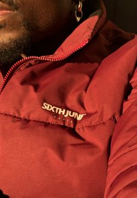 Κόκκινο αδιάβροχο μπουφάν με λεία υφή, διαθέτει πλήρη φερμουάρ και το λογότυπο "SIXTH JUNE" σε λευκό χρώμα στην περιοχή του στήθους.