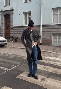 Szürke gyapjú keverék kabát, texturált kötött szürke pulóver, kék farmer, és fekete cipők, egy fekete sapkával kiegészítve. Városi jelenet zebrával.