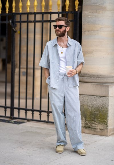 Camisa de manga corta ligera a rayas y pantalones anchos a juego en suave azul y blanco, combinados con zapatos beiges y gafas de sol.