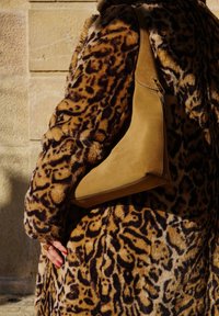 Καφέ σουέτ τσάντα ώμου με καμπυλωτό σχέδιο, σε συνδυασμό με μία υφασμάτινη γούνινη καμπαρντίνα σε λεοπάρ σχέδιο σε αποχρώσεις του καφέ και του μαύρου.