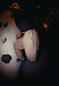 Pantaloni da arrampicata beige con una vestibilità ampia, realizzati in materiale durevole, con tasche e il logo "TERREX". Indossati con scarpe da arrampicata.
