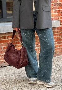 Σκούρο γκρι σακάκι, ξεθωριασμένα τζιν καμπάνα σε σχήμα, με λευκές τρουκς, επενδυμένη μπορντό τσάντα και ασημένια αθλητικά παπούτσια σε υφή.