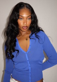 Cardigan bleu côtelé avec col en V et manches longues, doté de six boutons sur le devant et d'une coupe ajustée.