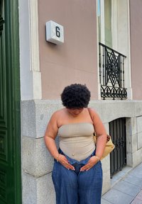 Rudos spalvos be petnešėlių viršus ir plačios džinsinės kelnės. Auksiniai papuošalai kaip akcentai. Smėlio spalvos siena ir akmeninis pagrindas su juoda tvorele ir skaičiaus 6 ženklu.