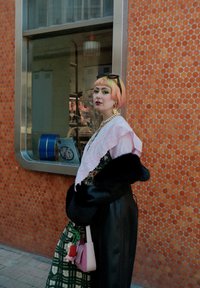 Kolorowy strój z różowym haftowanym szalem, czarnym sztucznym futrem, zieloną spódnicą w kratę i małą różową torebką z ozdobnymi zawieszkami.