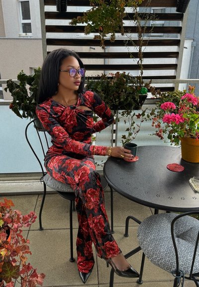 Mono ajustado con estampado floral en negro y rojo, con mangas largas y un diseño de frente anudado. Tacones negros de punta completa el look.