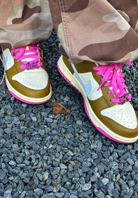 Sneakers Nike Dunk low in marrone, crema e rosa, con una punta perforata, lacci a contrasto e una suola in gomma rosa.