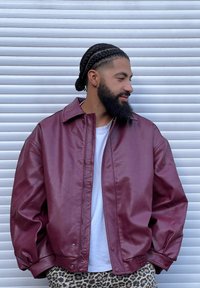 Bordowa skórzana kurtka o luźnym kroju, z dużym kołnierzem, zatrzaskami i ściągaczem u dołu. Noszona na białej koszulce i spodniach w panterkę.