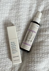 Diepe Slaap Kussen Spray en Ontspannende Lavendel sprayflessen op een gestructureerde witte stoffen achtergrond.