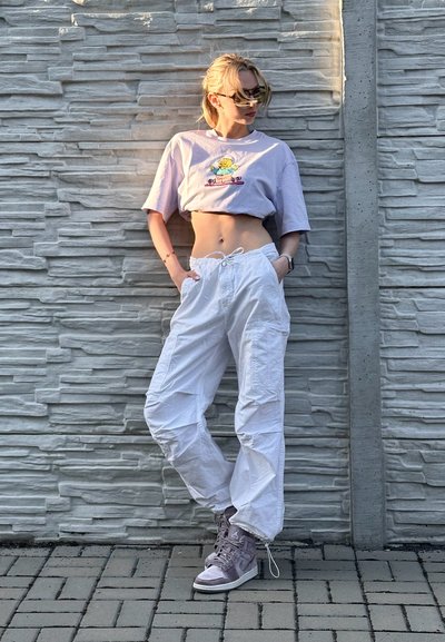 Pantalones cargo blancos con cinturilla elástica, una camiseta corta en lavanda con un dibujo animado, y zapatillas altas de color púrpura claro.