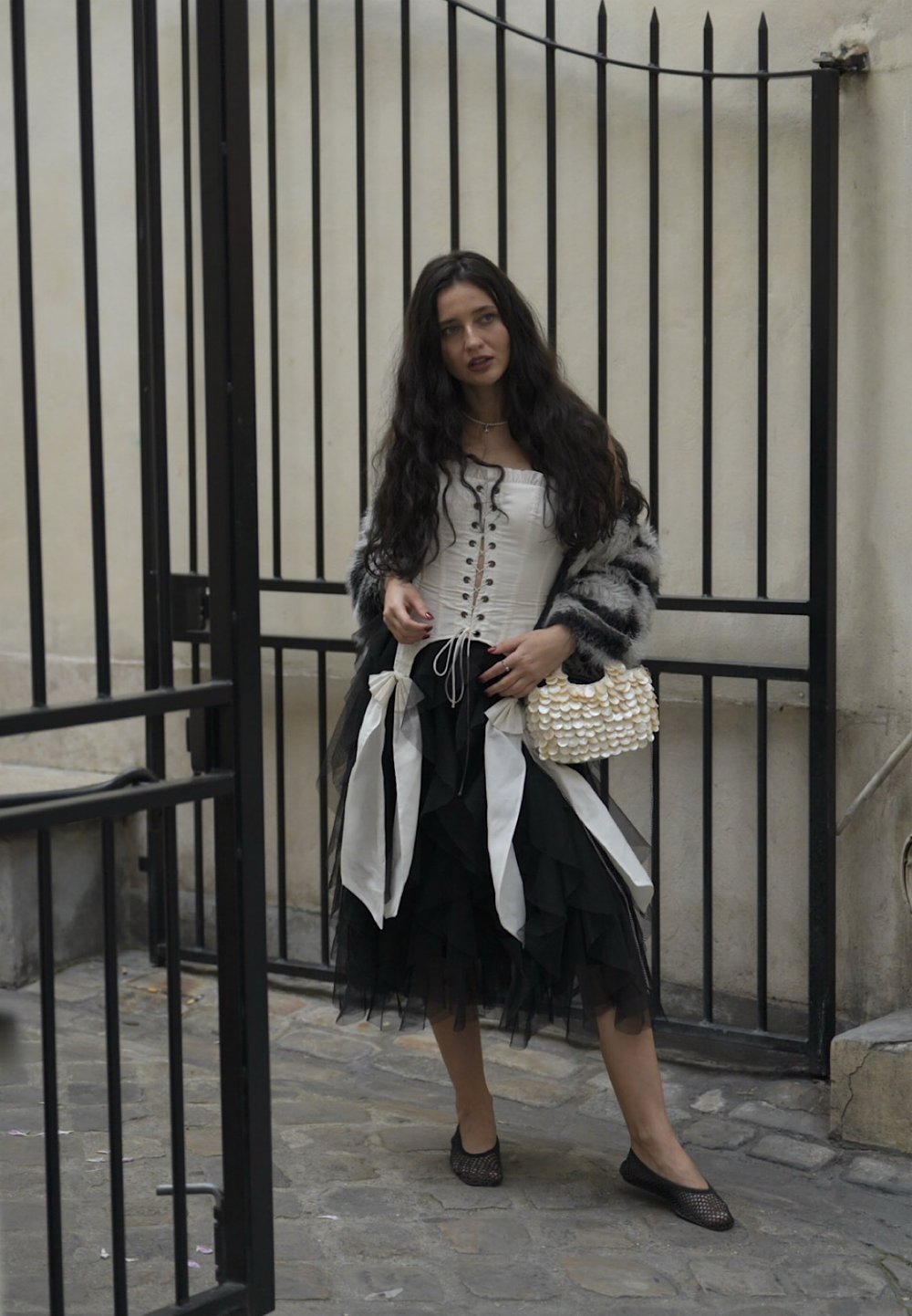 Mustriga must rüüde seeliku paaristamine valge pitsiga ülemise ja halli kunstkarusnahast kardiganiga. Väike pärlitega käekott lisab detaili. Musta võrkkanga tasased kingad lõpetavad välimuse.