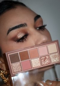 Øyenskyggepalett med ni nyanser i brunt, rosa og glitter. Paletten har et gjennomsiktig deksel og et slankt, rektangulært design.