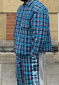 Camisa e calças de padrão xadrez nas cores azul, preto e branco. Corte largo com um bolso frontal na camisa e o texto "NIGHT" nas calças.