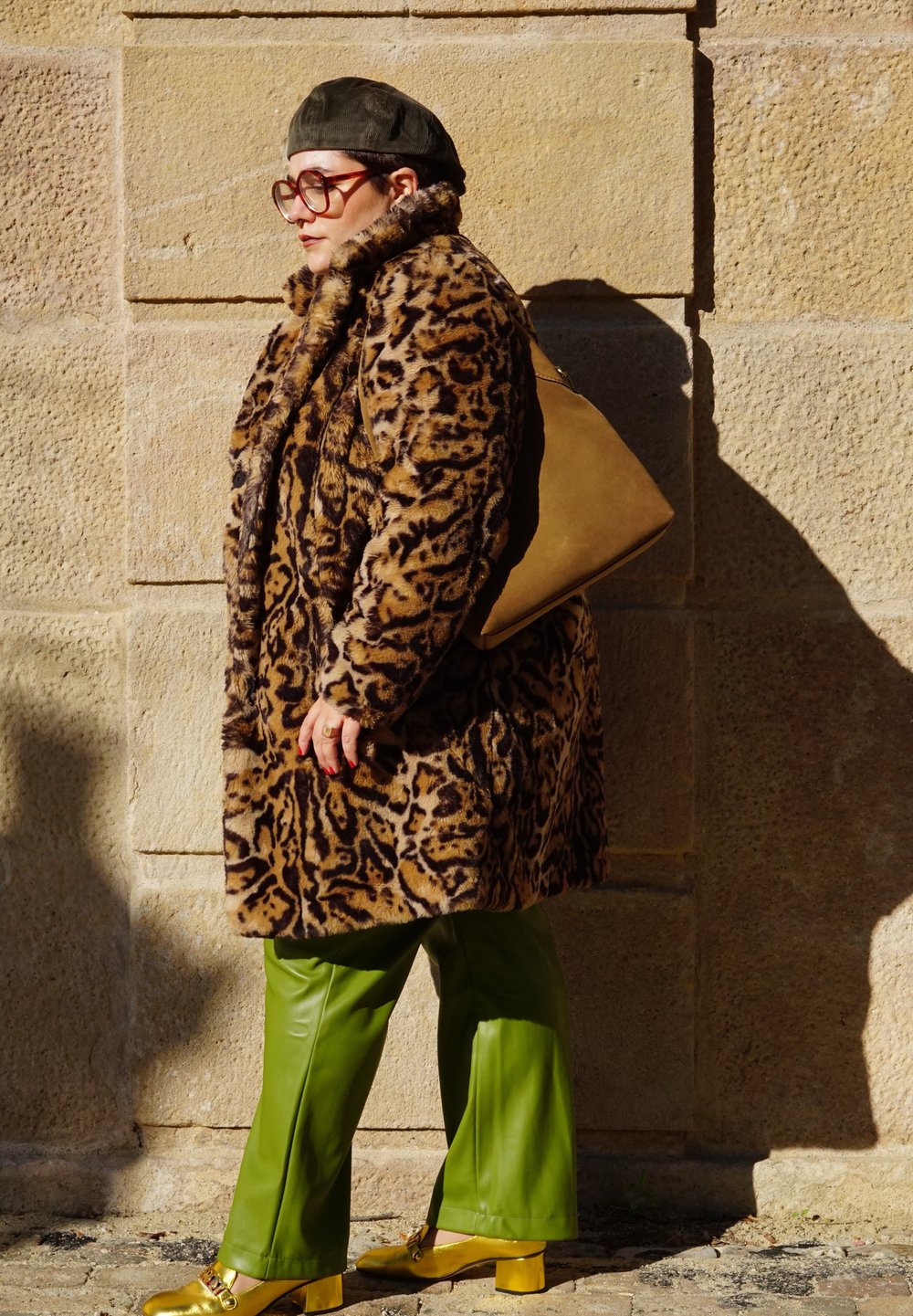 Παλτό από ψεύτικη γούνα με λεοπάρ σχέδιο, πράσινα δερμάτινα παντελόνια και κίτρινες μπλοκ-τακούνες παπούτσια. Μεγάλα στρογγυλά γυαλιά, καπαρντίνα σε χακί χρώμα και ταμπά τσάντα.