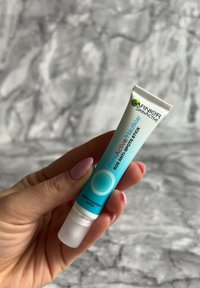 Bâton anti-taches Garnier Pure Active SOS dans un tube bleu vif avec des accents blancs, présentant un embout applicateur transparent et des éléments de design circulaires.