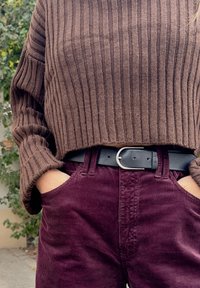 Brown ribbed knit sweater paired with dark burgundy corduroy trousers and a black belt with a silver buckle.