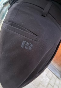 Μαύρα παντελόνια με πίσω τσέπη και απαλή υφή, διακοσμημένα με το λογότυπο "P3" σε ανάγλυφη μορφή. Το ύφασμα φαίνεται ελαφρώς χνουδωτό.