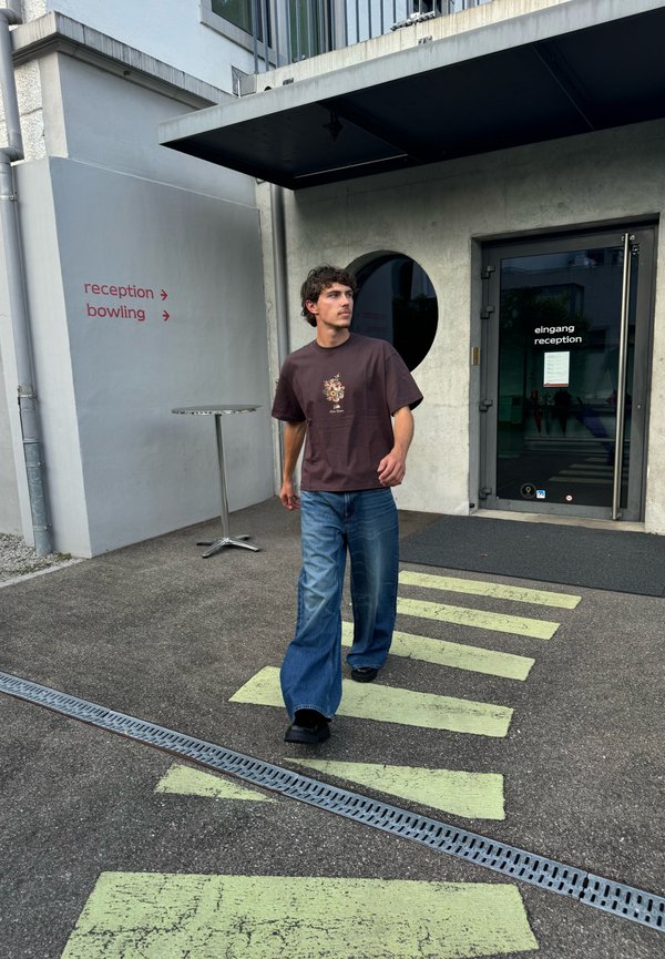 Man walking on yellow-striped crosswalk outside building with reception and bowling signs on gray walls.