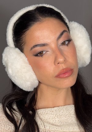 Orejeras de piel sintética blanca con un diseño acolchado, que presentan una textura suave y una forma circular, llevadas sobre cabello oscuro contra un fondo neutro.