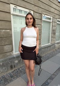 Balta raštuota maikutė, derinama su juoda raukšlėta mini sijonu. Aksesuarai – maža pintinė juoda rankinė ir rožinės sandalai su dirželiais.