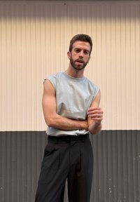 Gaiši pelēks bezdelīgas kreklis ar augstu jostasvietu melnam biksēm, kuram ir brīva forma un gluda auduma tekstūra.