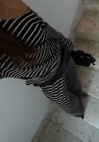 Tenue à rayures noires et blanches avec manches longues, pantalons à jambes larges et ceinture noire. Tissu texturé et chaussures noires pointues visibles.