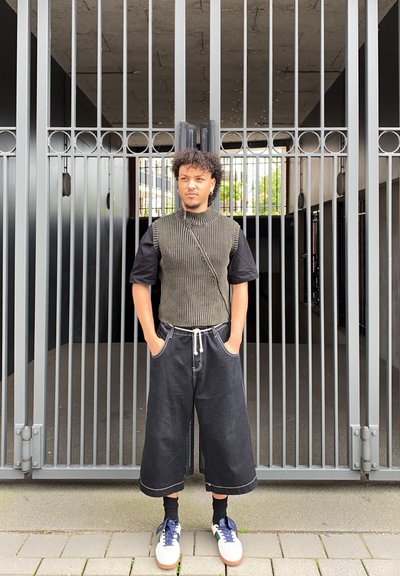 Top sin mangas de punto con textura acanalada en verde oliva, combinado con culottes negros holgados y zapatillas blancas con acentos azules.