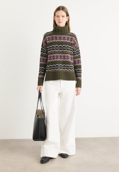 Suéter acogedor de color verde oscuro con patrones de fair isle coloridos, cuello alto y dobladillo acanalado. Combinado con pantalones anchos blancos y un bolso tote negro.