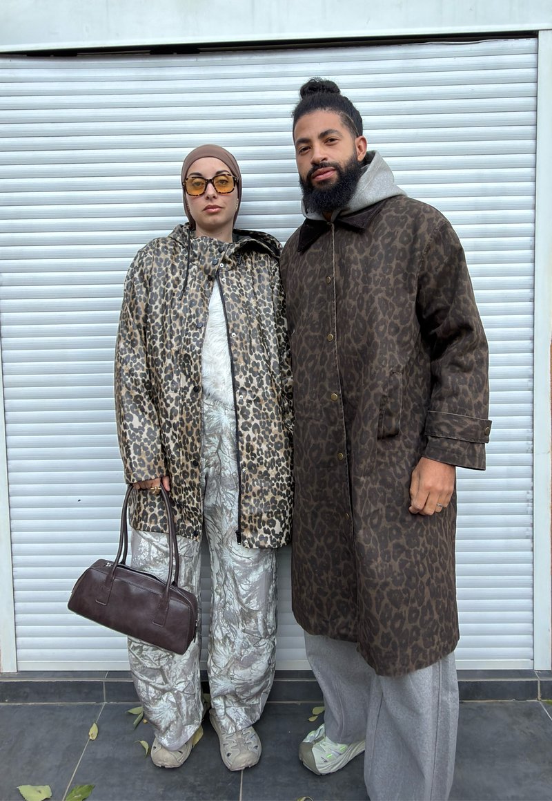 Manteau et pantalon imprimé léopard aux nuances de brun et beige, assortis à une tenue grise texturée et un sac à main marron, sur un fond clair.