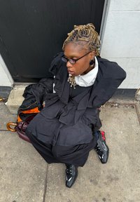 Ținută stratificată neagră cu design cu volane, guler alb și țesătură texturată. Adidași negri cu accente roșii și accesorii cu mărgele.