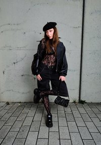 Μαύρη δερμάτινη τζάκετ bomber πάνω από ένα κορμάκι από δαντέλα, συνδυασμένο με μαύρες βερμούδες και κολάν από δαντέλα. Μια μαύρη μπερέ και παπούτσια με χοντρή σόλα ολοκληρώνουν την εμφάνιση.