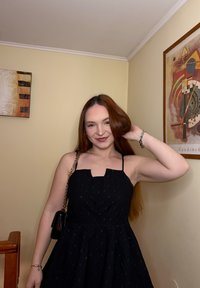 Robe noire avec un corsage cintré, de fines bretelles et une jupe évasée. Dotée d'un décolleté carré et d'une texture subtilement texturée. Sac à main noir.