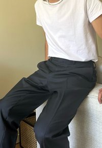 T-shirt branca de manga curta combinada com calças pretas, ajustadas. As calças têm uma textura suave e bolsos frontais. Design simples e clássico.