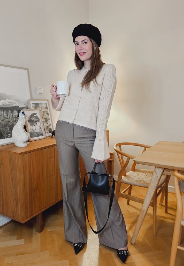 Bež kudumi cardigan lühikese hemiga, halli triibuga laiad püksid, must beret, must käekott ning terava nina ja studsiga kingad.
