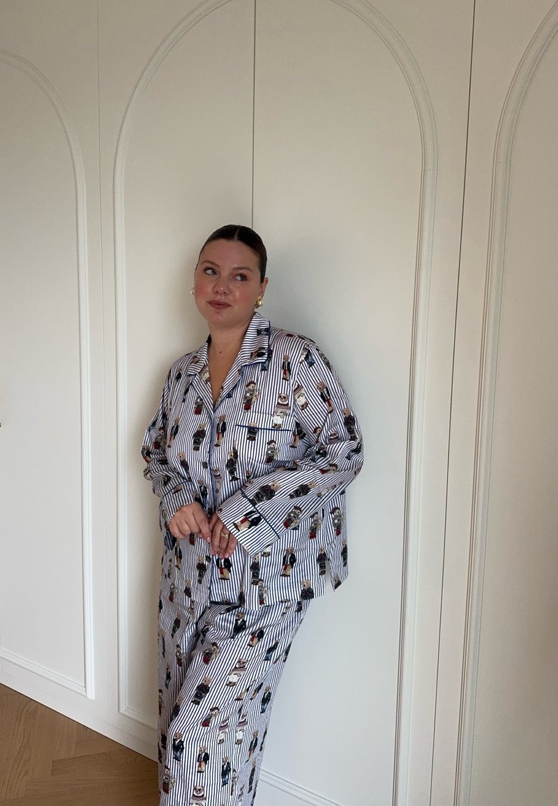 Gestreept pyjama set met kleurrijke cartoonfiguren, gemaakt van zachte stof. De top heeft een notched kraag en knoopsluiting, met loszittende broek.