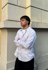 Camicia a righe blu e bianca con un taglio rilassato, abbinata a pantaloni neri. Il tessuto appare liscio con un colletto classico.
