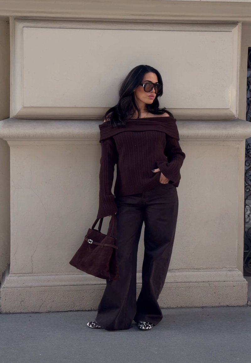 Pull marron côtelé décolleté avec des manches longues, associé à un pantalon marron à jambes larges et un sac à main en daim marron.