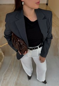 Textúrované čierno-biele kockované sako, čierny top, biele široké nohavice, hnedé pletené psaníčko, strieborné lodičky so špicatou špičkou, veľké strieborné náušnice.