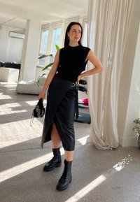 Juoda berankovė palaidinė derinama su juoda aukštu liemeniu, dirbtinės odos apsiaustu-šortais, turinčiais šoninį įpjovimą ir sidabro žiedu. Juodos su raišteliais botai.