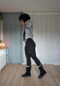 Black leggings, grey zip-up hoodie, and black fur-lined boots. Textured fabric, sleek design, minimal Nike logo on the leggings.
