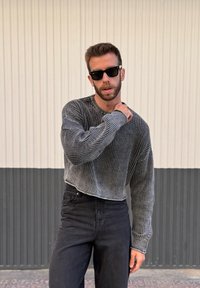 Pullover tricotat cu dungi negre și gri, cu mâneci lungi, guler rotund și croială scurtă, asortat cu blugi negri cu talie înaltă.