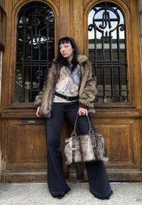 Cappotto in pelliccia sintetica marrone, top con motivo, jeans neri a zampa e borsa marrone con dettagli in pelliccia, dotata di ferrature dorate e doppi manici.