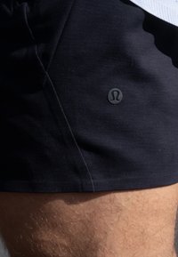 Marineblaue Shorts aus leichtem Material, mit einem kleinen schwarzen Logo an der Seite, glatter Oberfläche und elastischem Bund.