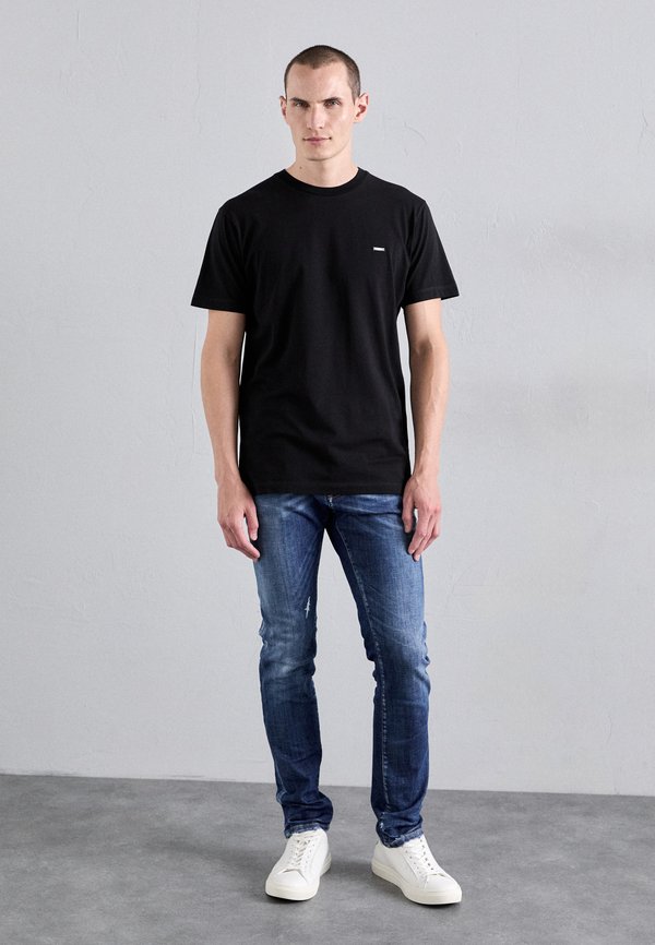 Black cotton t-shirt with a crew neck, teamed with distressed blue jeans and white trainers. Simple design, fitted silhouette.