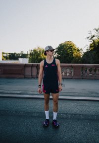 Sportigt set bestående av en marinblå linne med rosa detaljer och matchande shorts, vita strumpor och mörka skor med rosa inslag. Kepa och solglasögon bärs.